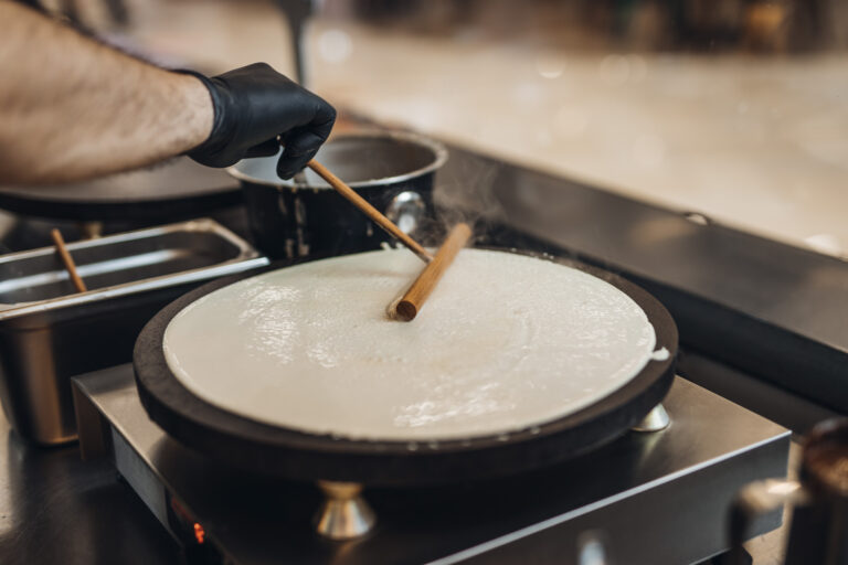 Close up shot of male worker's hand making delicious sweet and salted pancakes.